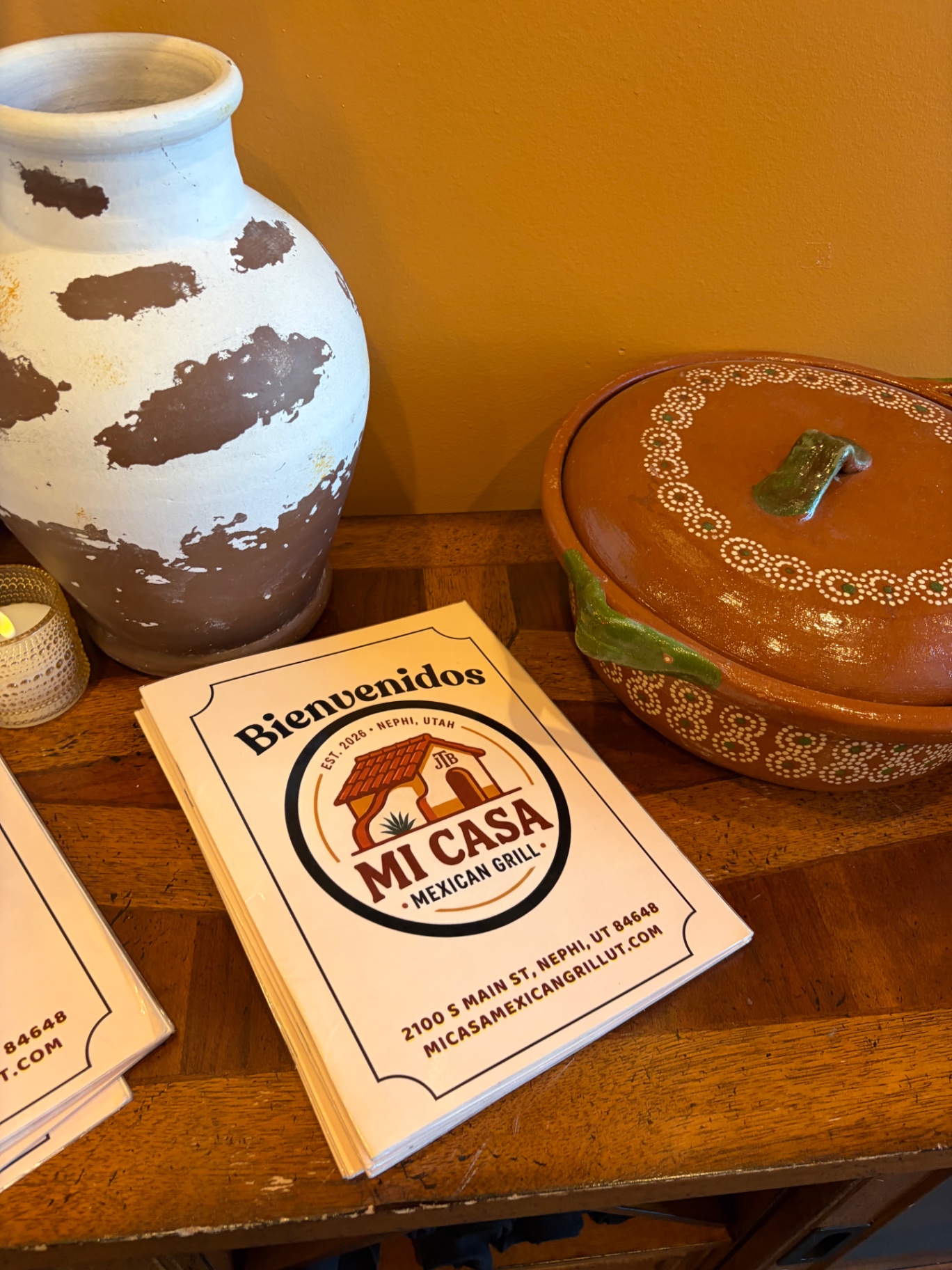 Mi Casa Mexican Grill menu with the restaurant's logo, address, and hand-painted pottery on a wooden sideboard