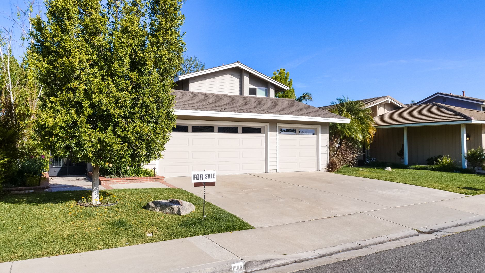 A small, well-kept starter home with a tidy front yard on a sunny day