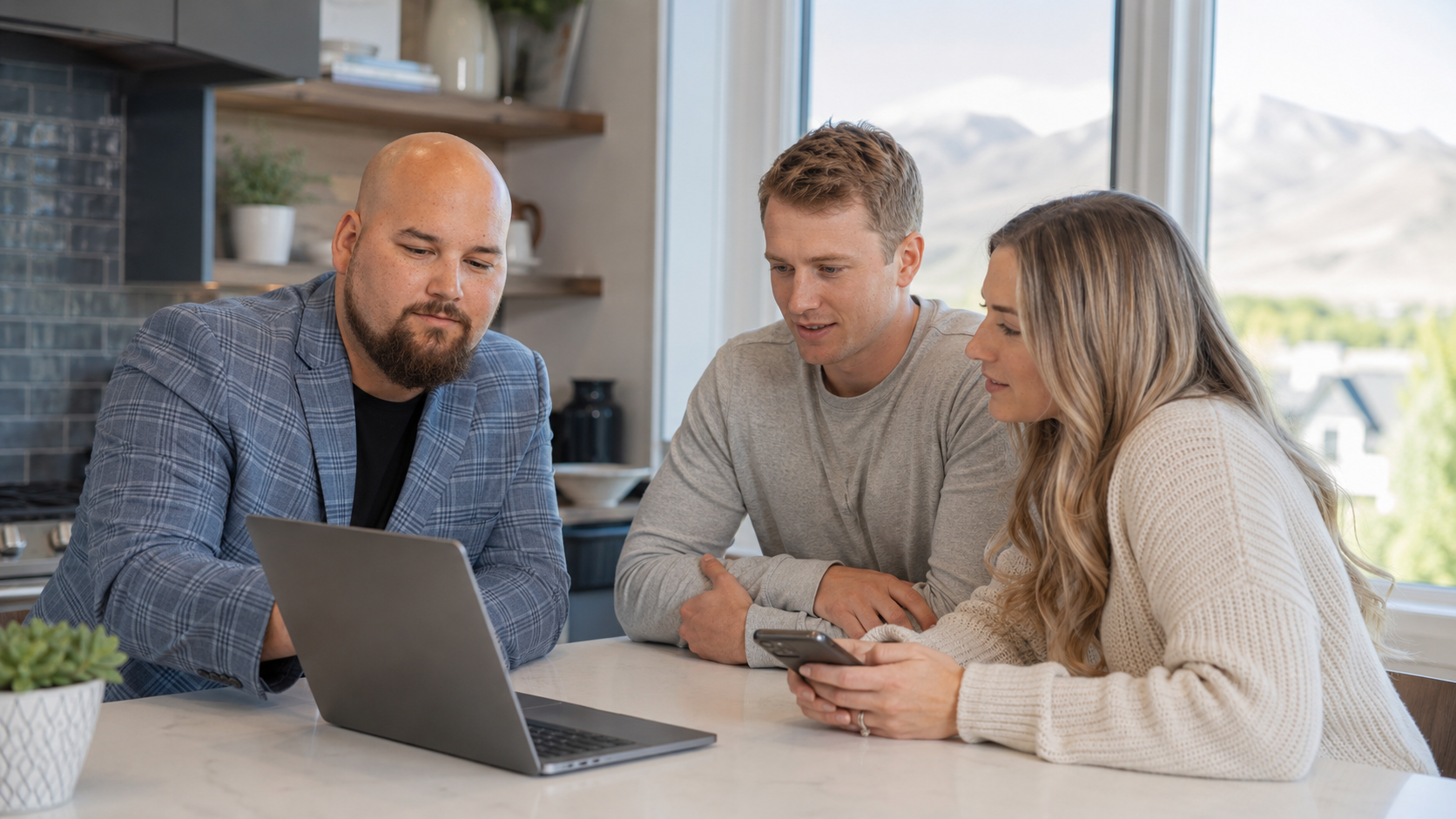 Dana Hoyt reviewing online home listings on a laptop with a buyer couple in a Central Utah kitchen