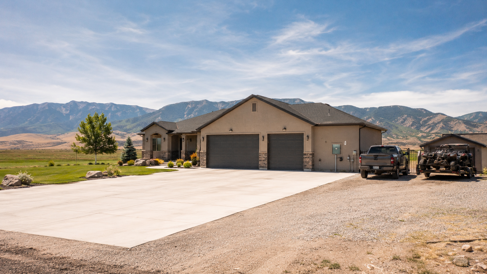 A Juab County home with a deep driveway, three-car garage, and a travel trailer parked on a side pad